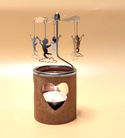 Kerzenkarussell mit natürlichem Zimtrinden-Teelichthalter, Glaseinsatz und rotierenden Metallanhängern, wahlweise mit Herz- oder Tannenbaum-Motiv.