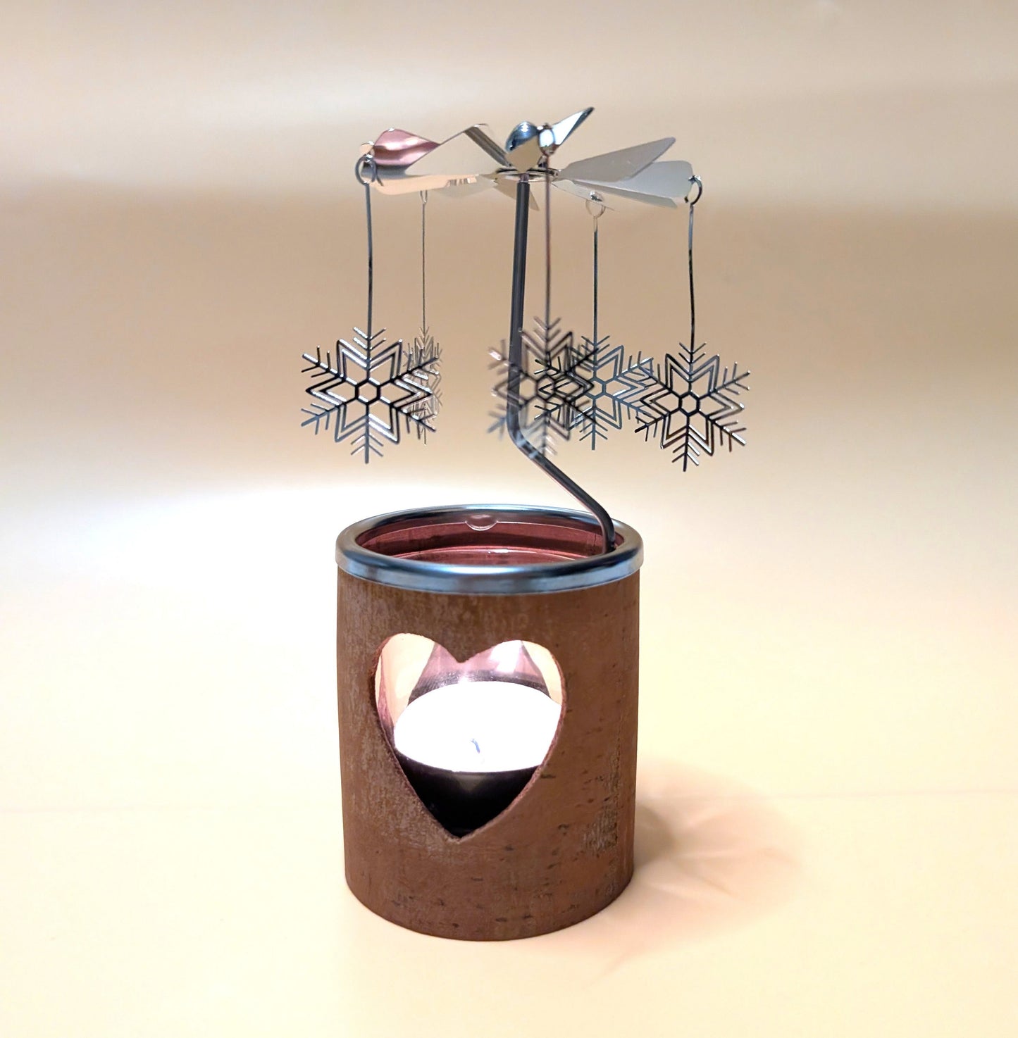 Kerzenkarussell mit natürlichem Zimtrinden-Teelichthalter, Glaseinsatz und rotierenden Metallanhängern, wahlweise mit Herz- oder Tannenbaum-Motiv.