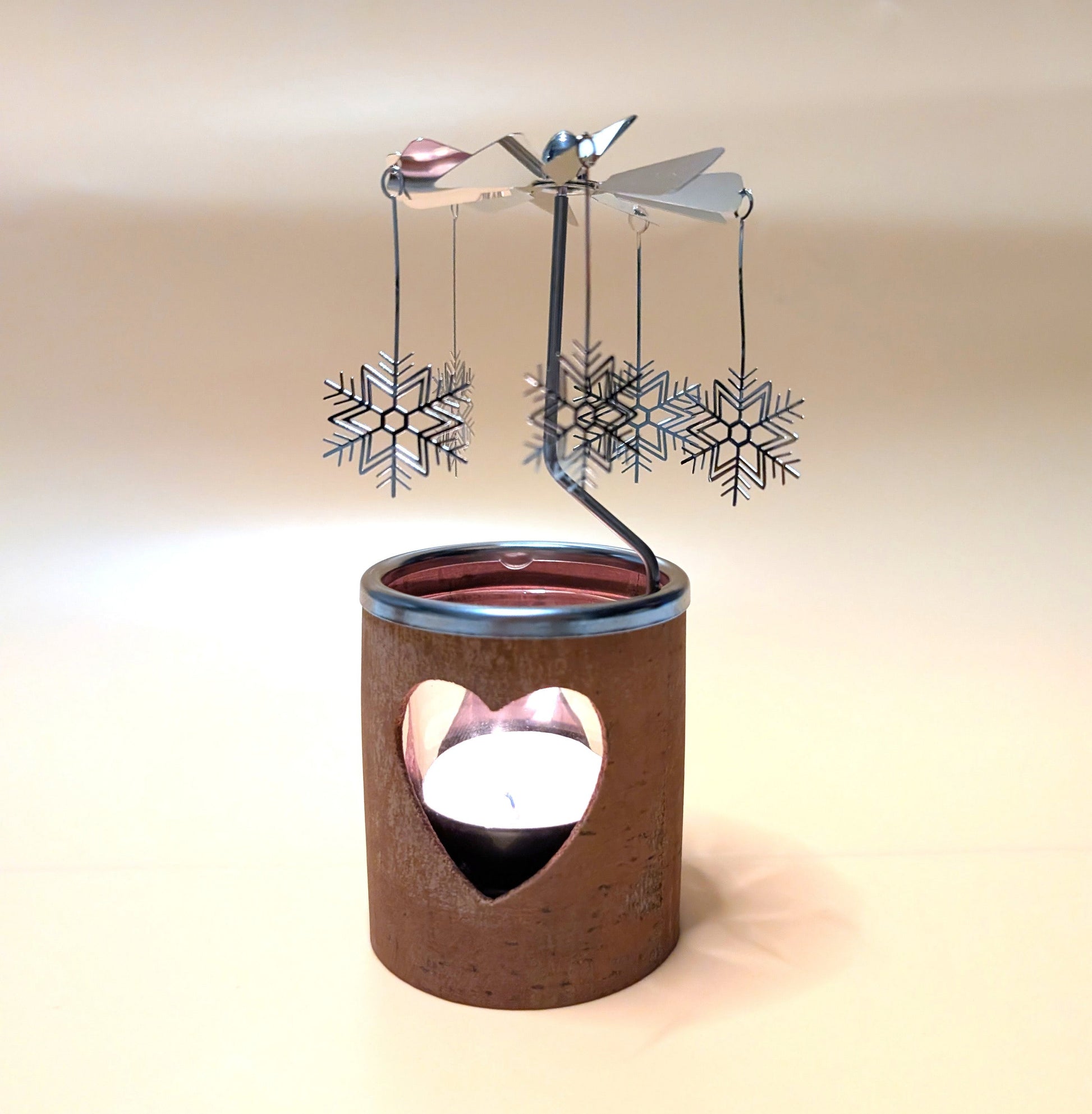 Kerzenkarussell mit natürlichem Zimtrinden-Teelichthalter, Glaseinsatz und rotierenden Metallanhängern, wahlweise mit Herz- oder Tannenbaum-Motiv.