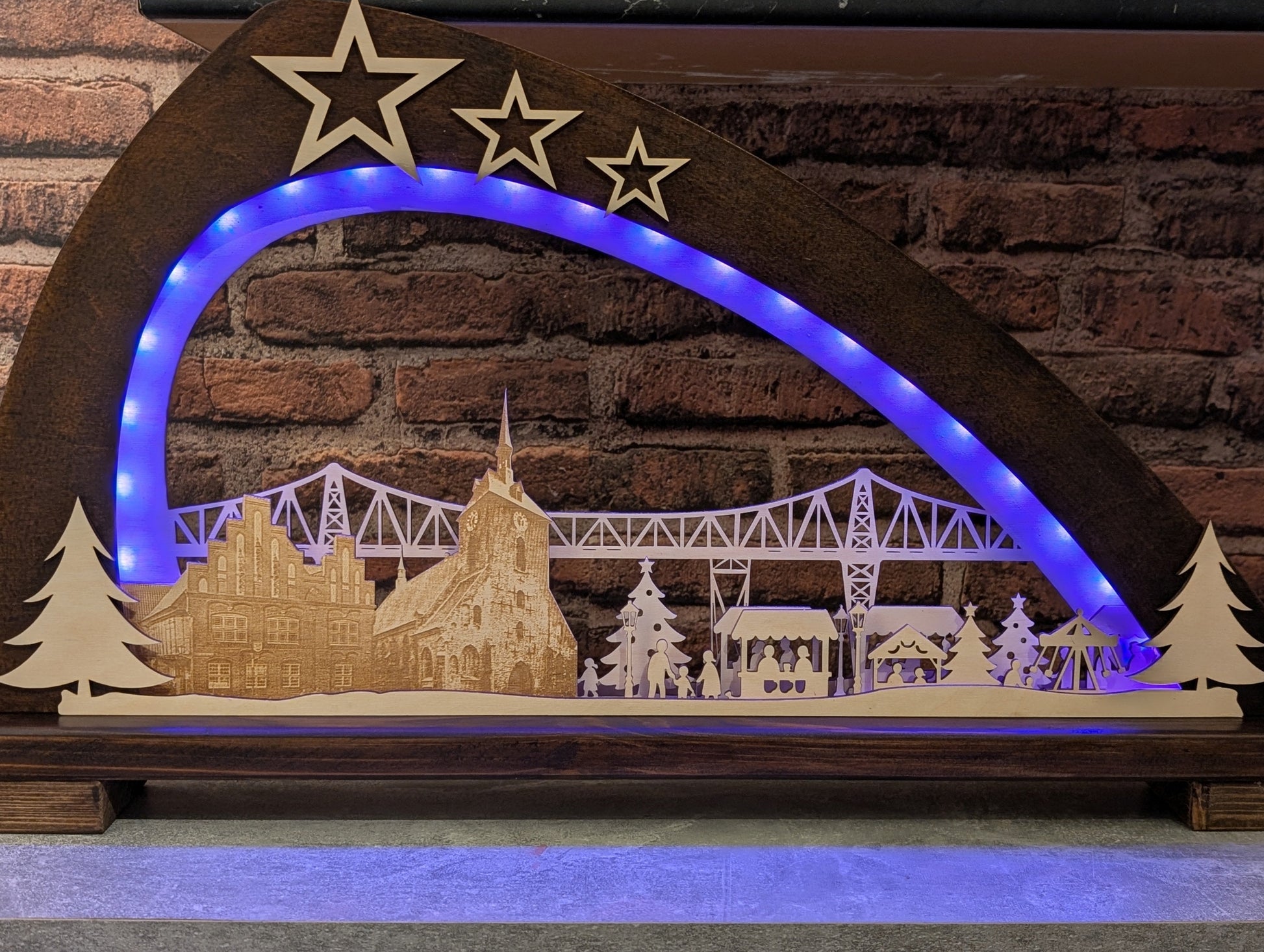 Handgefertigter Schwibbogen aus Birkenholz mit LED-Beleuchtung, zeigt Rendsburger Eisenbahnhochbrücke, Altes Rathaus, Marienkirche und Weihnachtsmarkt.