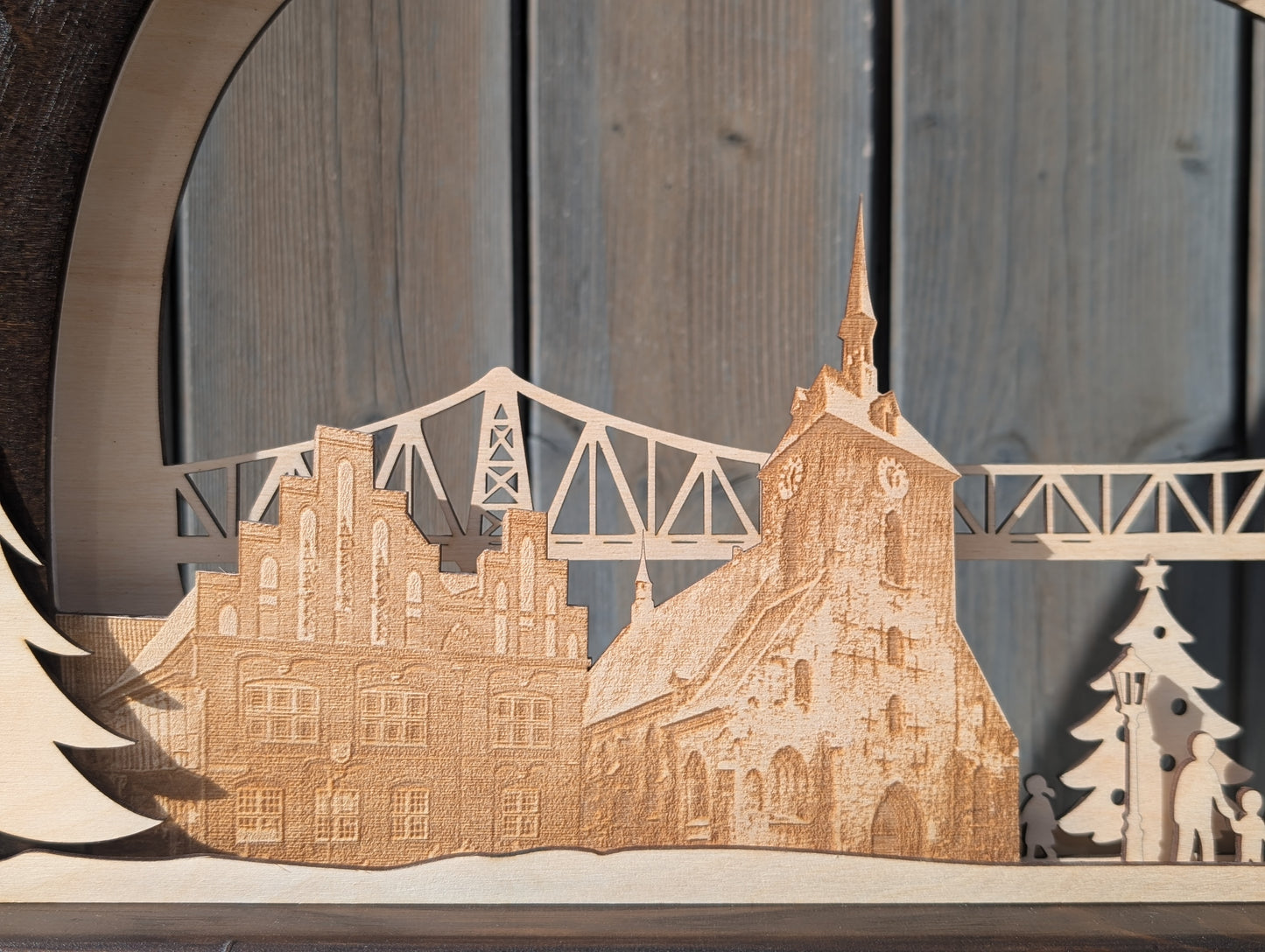 Handgefertigter Schwibbogen aus Birkenholz mit LED-Beleuchtung, zeigt Rendsburger Eisenbahnhochbrücke, Altes Rathaus, Marienkirche und Weihnachtsmarkt.