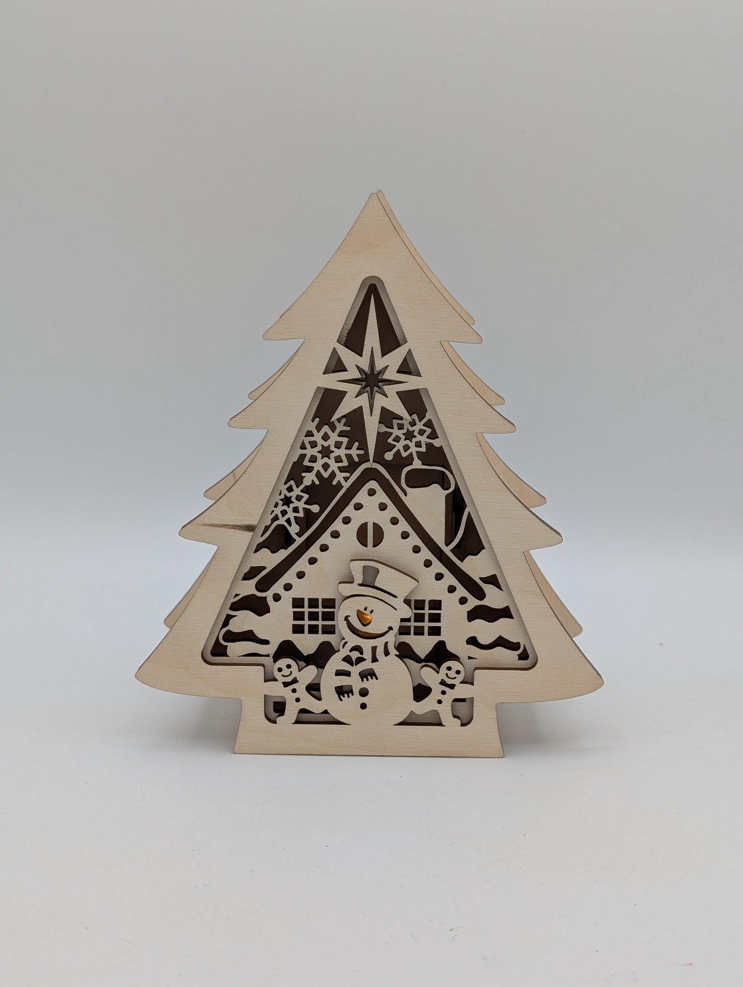 Beleuchteter Holzbaum mit Schneemann und Hausmotiv