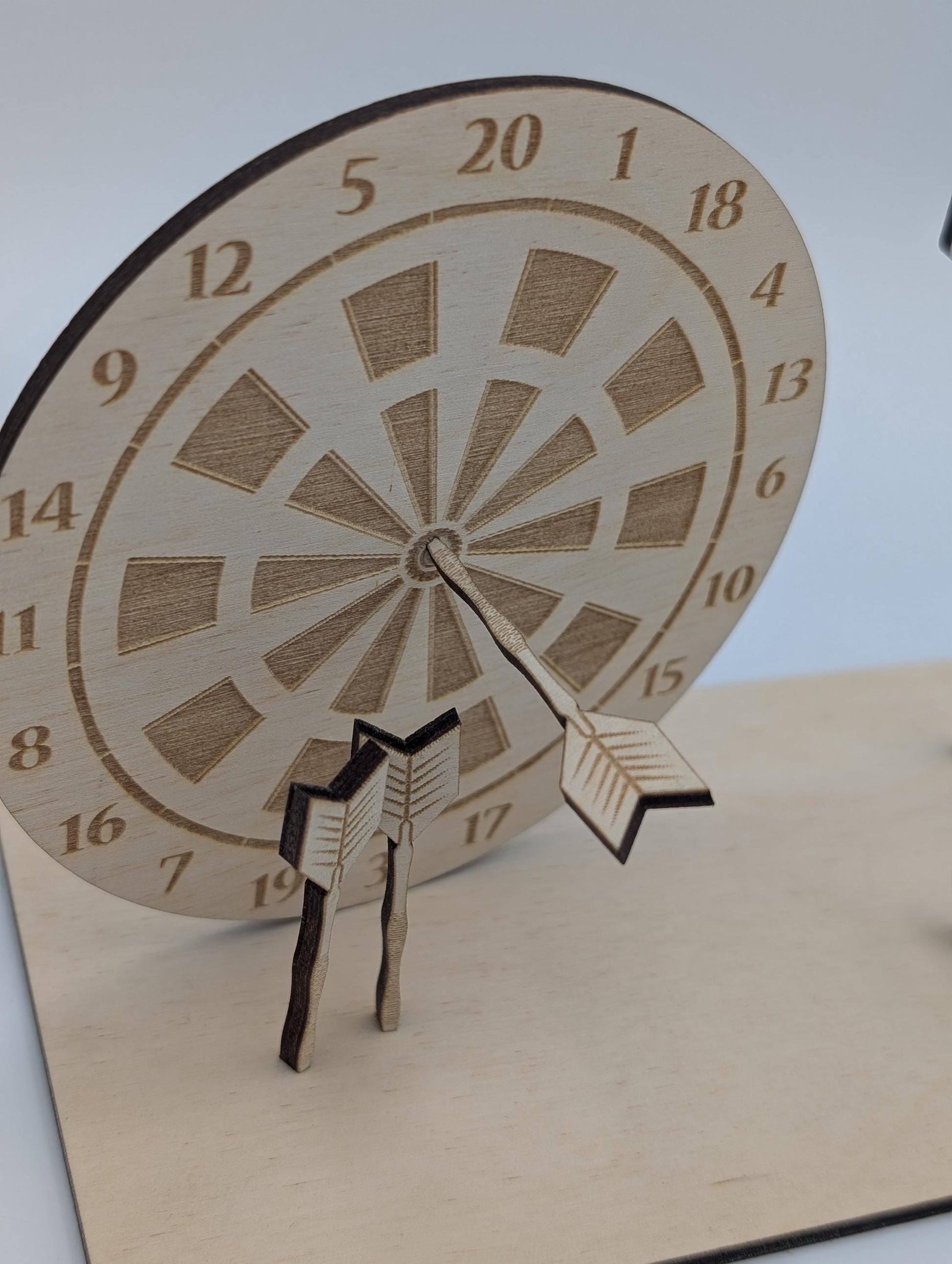 &quot;Personalisierte Dartscheibe aus Holz mit Gravur und Geldhalter, auf einer stabilen Bodenplatte befestigt. Ein Dartpfeil steckt in der Mitte der Scheibe, kann aber auf Wunsch auf eine bestimmte Punktzahl gesetzt werden. Das gravierte Schild zeigt „Happy Birthday – 180 Gründe zu feiern“ oder eine individuelle Widmung. Perfektes Geschenk für Dartspieler zum Geburtstag, Jubiläum oder als Pokal für ein Dartturnier.&quot;