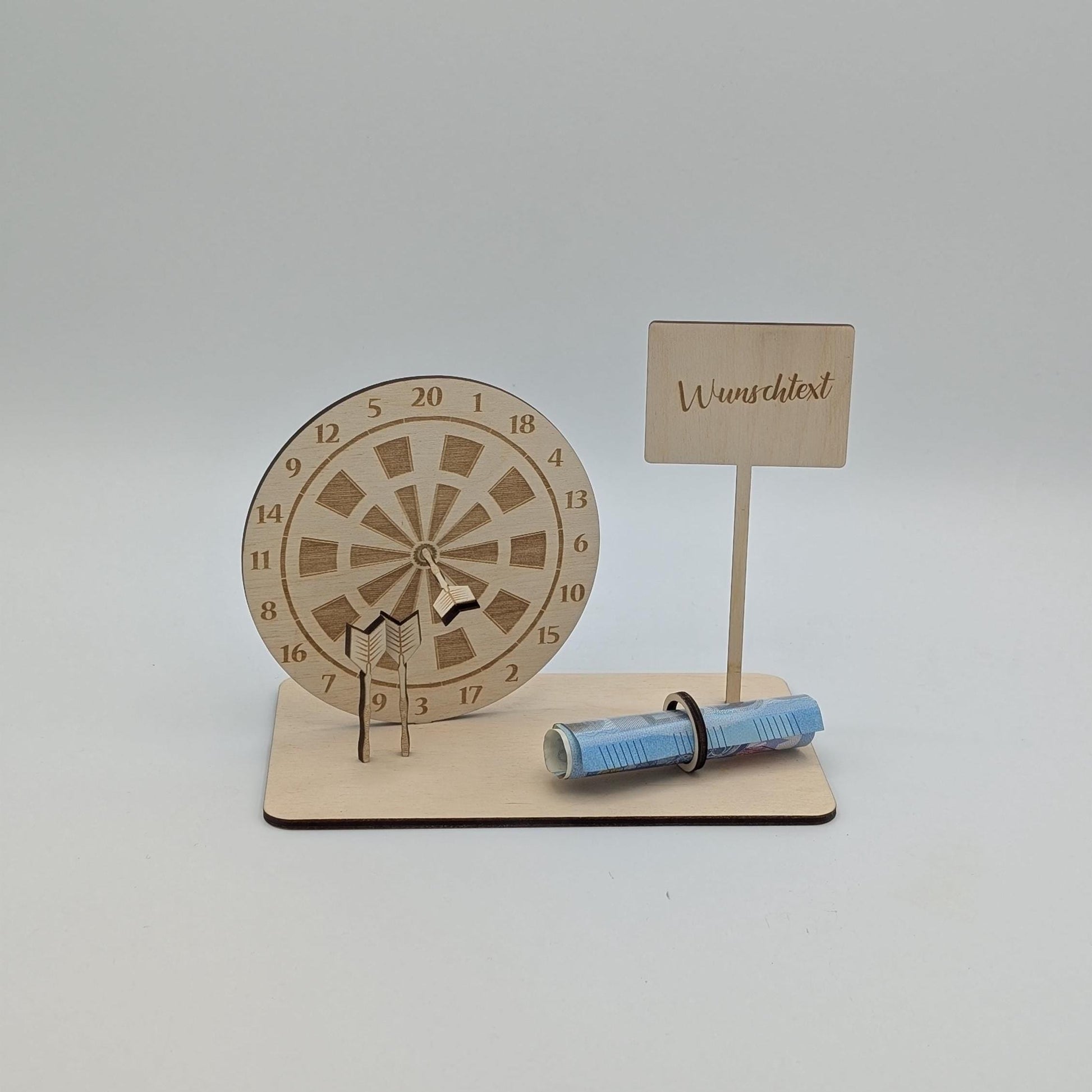 "Personalisierte Dartscheibe aus Holz mit Gravur und Geldhalter, auf einer stabilen Bodenplatte befestigt. Ein Dartpfeil steckt in der Mitte der Scheibe, kann aber auf Wunsch auf eine bestimmte Punktzahl gesetzt werden. Das gravierte Schild zeigt „Happy Birthday – 180 Gründe zu feiern“ oder eine individuelle Widmung. Perfektes Geschenk für Dartspieler zum Geburtstag, Jubiläum oder als Pokal für ein Dartturnier."